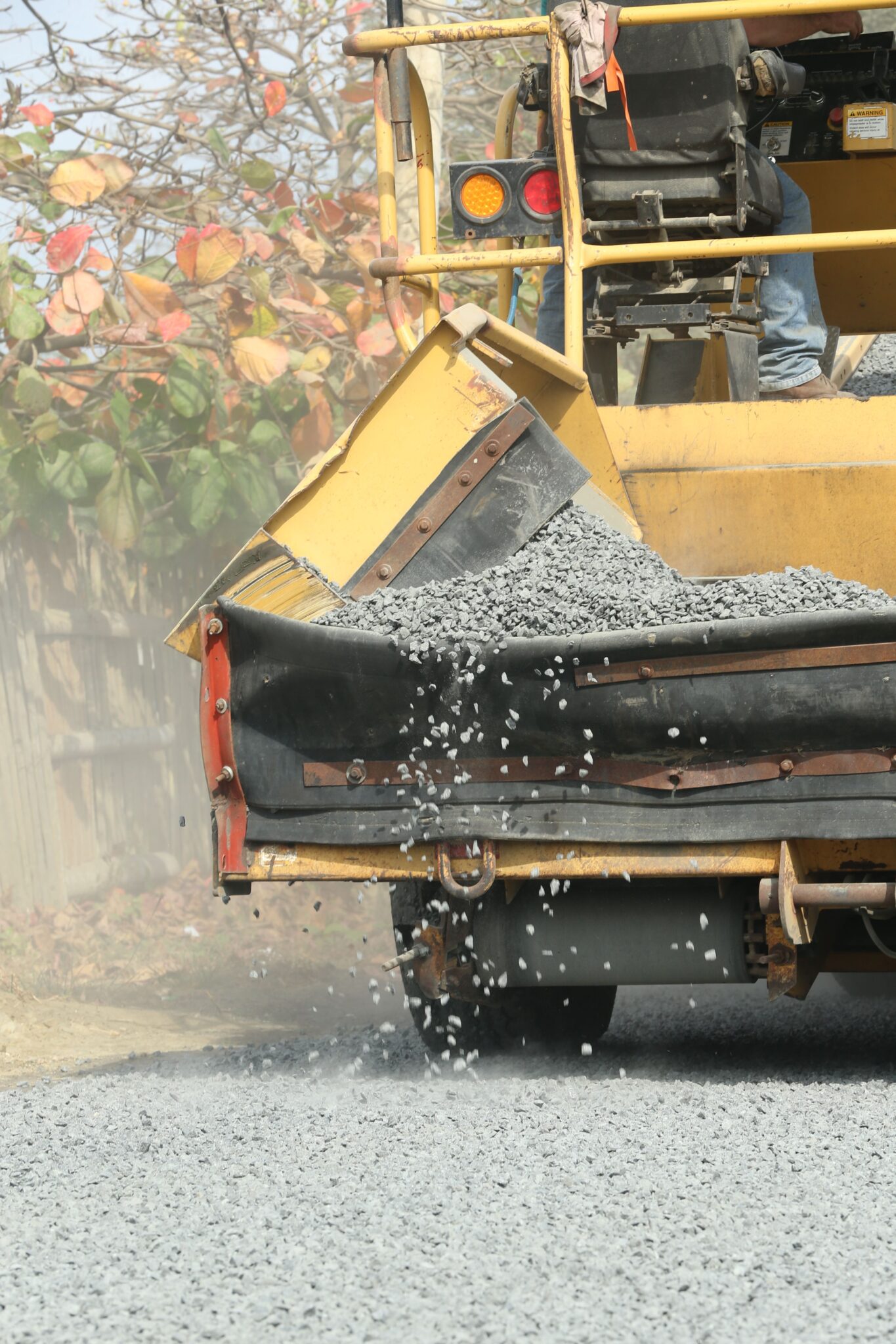 Machine spreading gravel over a construction work area